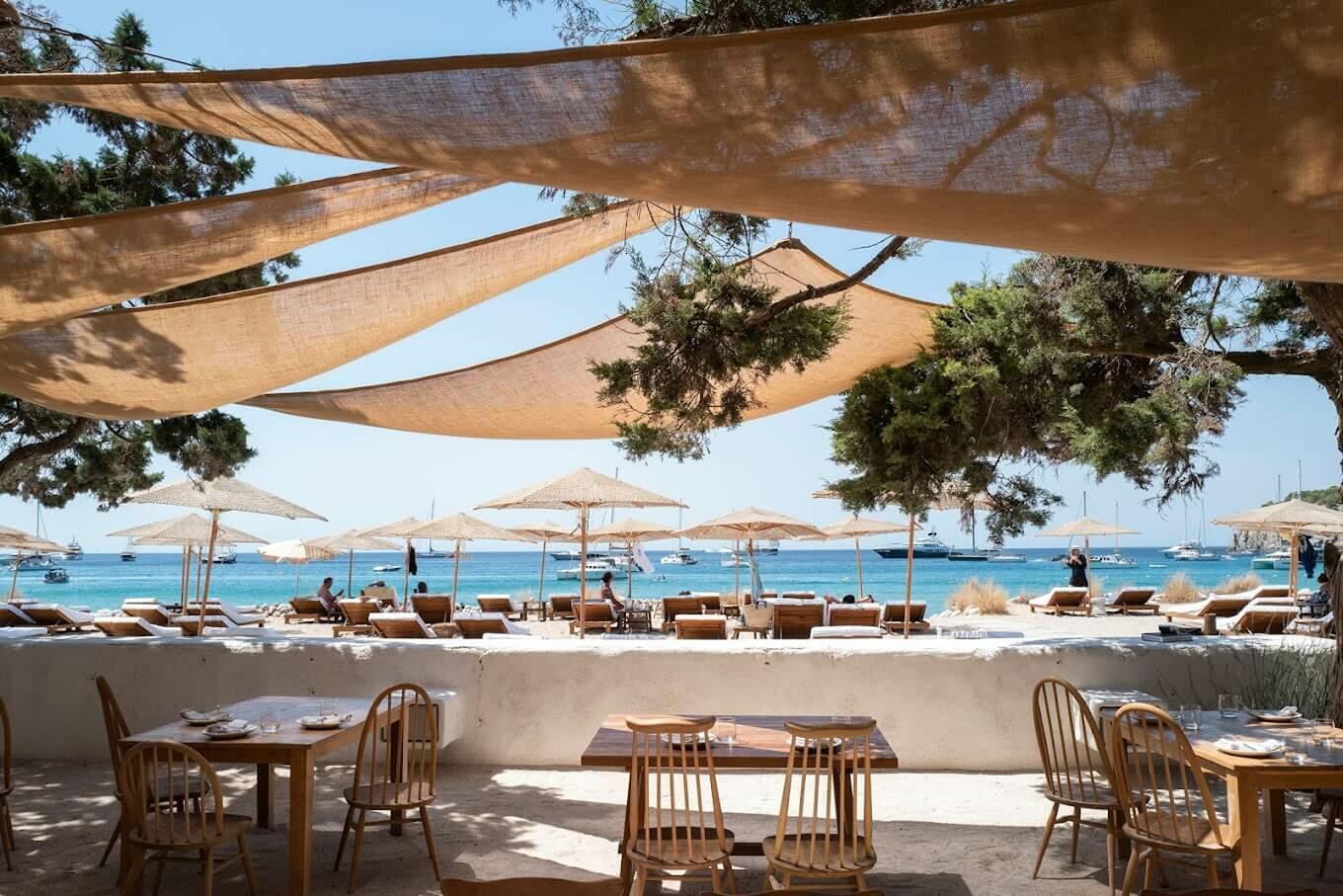 Casa Jondal: situada en una cala serena de aguas turquesas, Casa Jondal es sinónimo de elegancia discreta. Conocida por su marisco excepcional y su refinado menú mediterráneo, aquí los almuerzos largos y pausados se convierten en el momento estrella del día. El diseño es chic y a la vez relajado, con maderas naturales y linos suaves que crean una sensación costera sin esfuerzo. Jondal cierra a primera hora de la tarde-noche, por lo que es ideal para una escapada diurna antes de volver a casa para una velada familiar tranquila o para prepararse para la noche que viene.