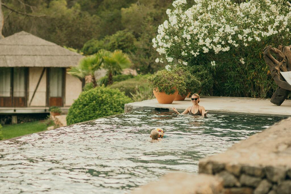 Piscina y jardín mediterráneo en Villa Paradiso en Ibiza, con huéspedes disfrutando del agua.