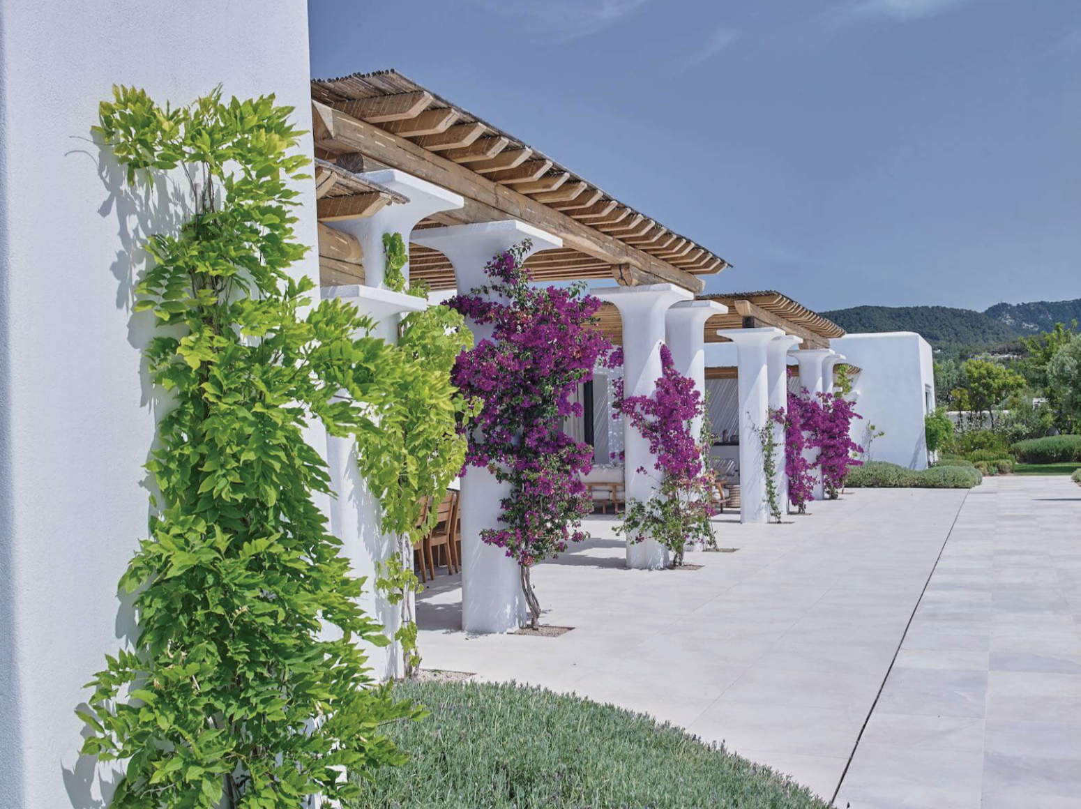 Villa Blakstad en Ibiza con paredes encaladas, pérgolas de madera, buganvillas trepadoras y jardines paisajísticos.